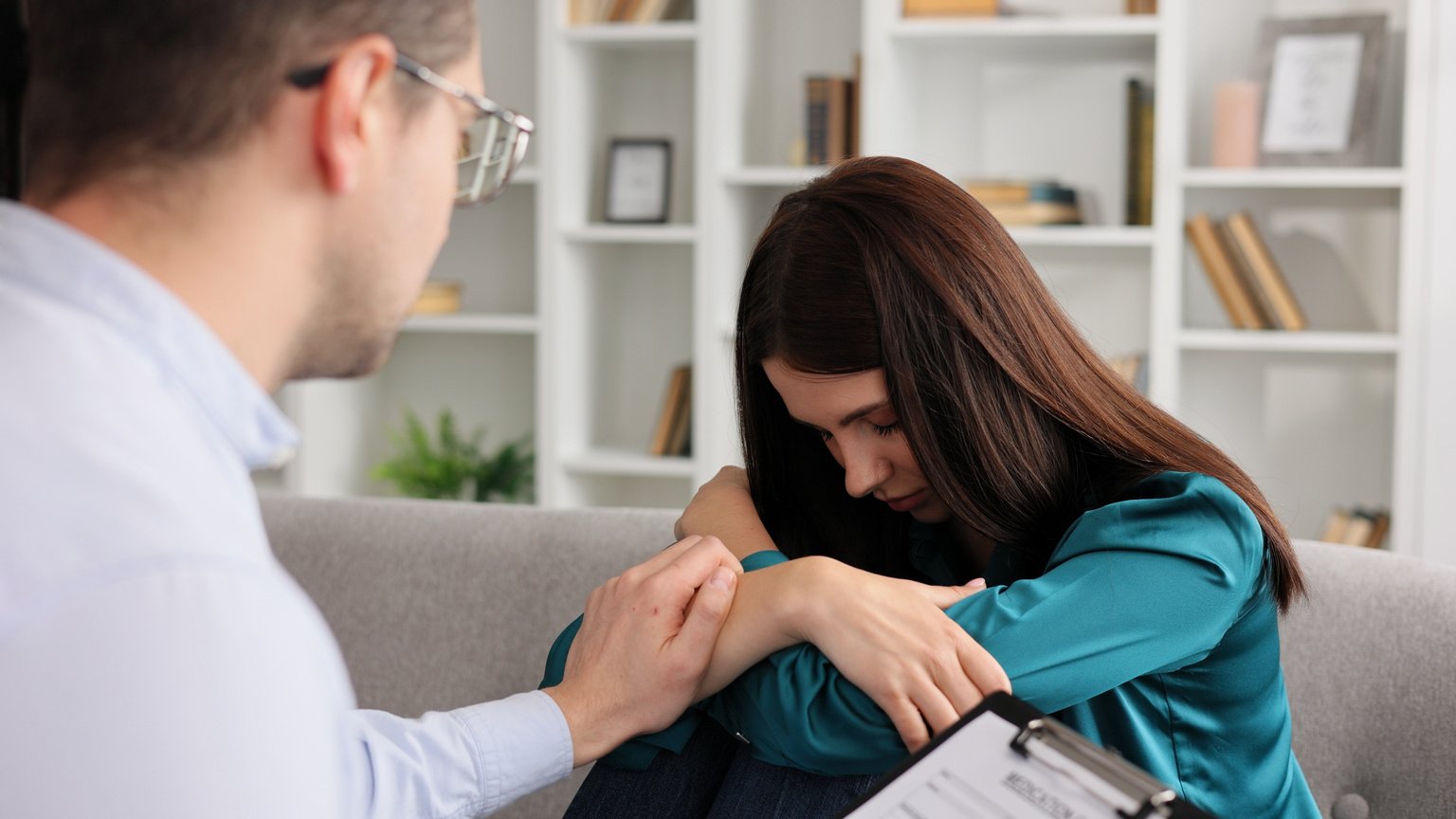 A male professional psychologist tries to comfort his depressed patient in despair by holding her hand. Mental illnesses, psychological counseling.